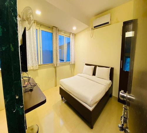 een slaapkamer met een bed met witte lakens en een raam bij Baba Ramdev Lodging And Veg Restaurant in Mahabaleshwar