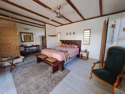 a large bedroom with a bed and a chair at Breeze Ocean Bungalow Moorea in Moorea