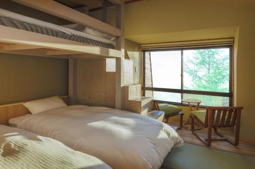 um quarto com 2 beliches, uma mesa e uma janela em Takamiya Hotel Jurin em Zao Onsen