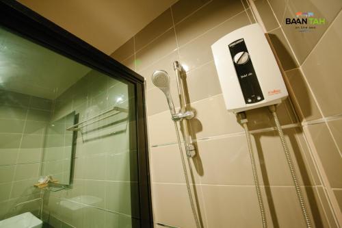 a shower in a bathroom with a hair dryer on the wall at Baan Tah On The Sea in Bang Sare