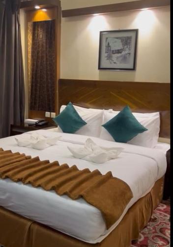 a large white bed with green pillows in a room at Sky View Hotel, Madinah in Al Madinah