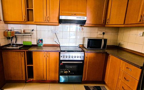 a kitchen with wooden cabinets and a stove and a microwave at Mount View Residencies in Colombo