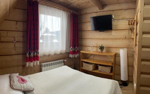 a bedroom with a bed and a tv and a window at Pokoje regionalne u Ani in Zakopane