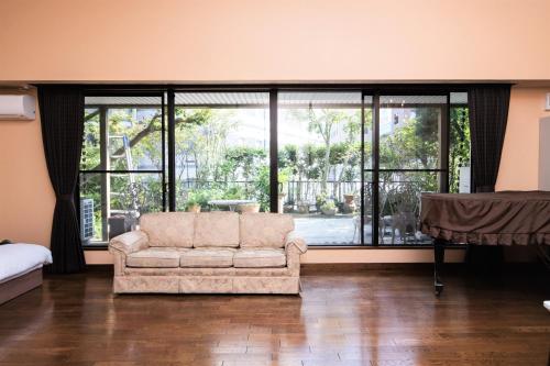 a living room with a couch and large windows at Arbor house in Kagoshima