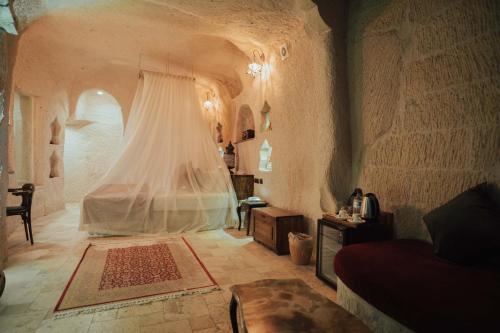 a bedroom with a bed with a curtain and a table at Hu of Cappadocia - Special Class in Uchisar