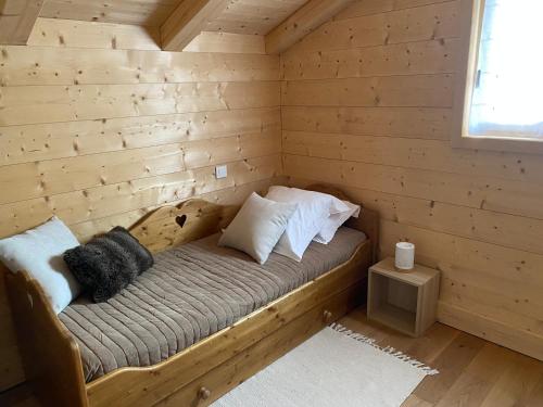 Una cama en una cabaña de madera con almohadas. en Chalet Charline, en Combloux
