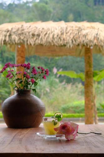 eine Vase mit Blumen und ein Getränk auf dem Tisch in der Unterkunft HÀ GIANG WOODEN HOUSE in Ha Giang