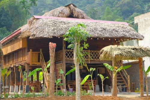 a hut with a straw roof and some trees at Ha Giang Wooden House in Ha Giang