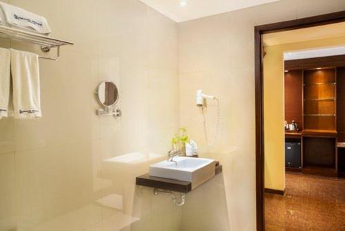 a white bathroom with a sink and a mirror at Grand Rohan Jogja in Yogyakarta