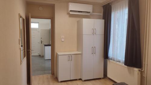una cocina con armarios blancos y una ventana en Belvárosi Apartman, en Pécs