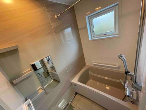 a bathroom with a tub and a sink and a window at Shallom Oiwake シャローム追分 in Oiwake