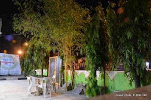 een groep tafels en stoelen onder de bomen 's nachts bij HOTEL SAIPRASAD LODGE Solapur in Solapur