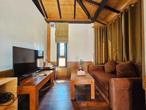 a living room with a couch and a tv at R1 Resort Rajapruek Chiangmai in Chiang Mai