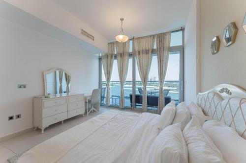 a white bedroom with a bed and a desk and a window at Holiday Apartment in Palm Jumeirah with Beach Access in Dubai