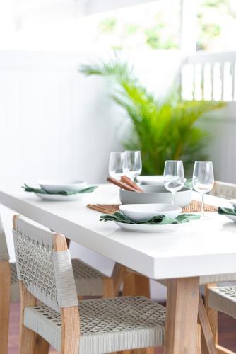 a white dining room table with wine glasses on it at The Elements l Earth l 4 Stunning Apartments each with Private Outdoor Dining l Walk to the Beach l Event Friendlyl Wifi l Netflix l Outdoor Shower l Communal BBQ Pavilion and Lawn Area l in Christies Beach