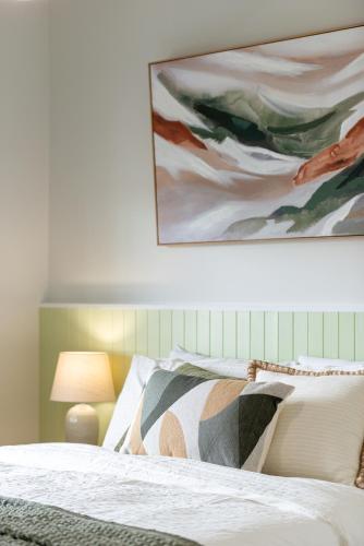 a bedroom with a bed with a painting on the wall at The Elements l Earth l 4 Stunning Apartments each with Private Outdoor Dining l Walk to the Beach l Event Friendlyl Wifi l Netflix l Outdoor Shower l Communal BBQ Pavilion and Lawn Area l in Christies Beach