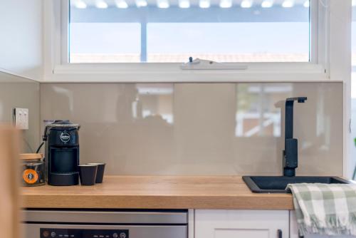 a kitchen with a counter top and a window at The Elements l Earth l 4 Stunning Apartments each with Private Outdoor Dining l Walk to the Beach l Event Friendlyl Wifi l Netflix l Outdoor Shower l Communal BBQ Pavilion and Lawn Area l in Christies Beach