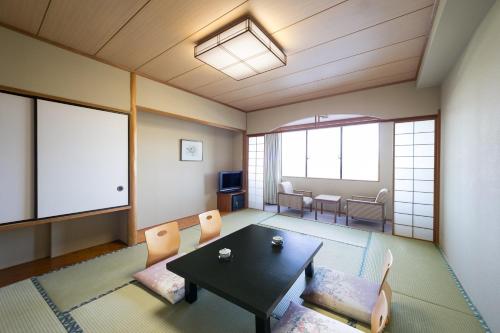 a living room with a table and chairs and a room withwindows at Grand Mercure Nasu Highlands Resort & Spa in Nasu
