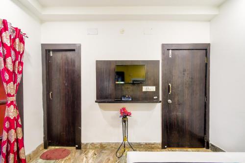 2 puertas de madera en una habitación con un jarrón de flores en Puja Residency, en Thākurdwari