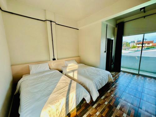 a bedroom with two beds and a large window at BureeSateng Hotel in Yala