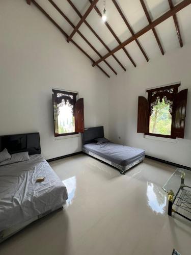 2 Betten in einem Zimmer mit 2 Fenstern in der Unterkunft Villa Kaki Bukit Ciwidey in Cisondari