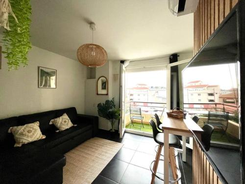 un salon avec un canapé noir et une table dans l'établissement Appart T2 Calme - Centre de Canet - Parking - Clim, à Canet