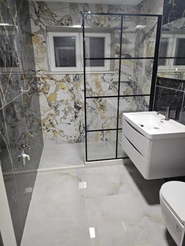 a bathroom with a white sink and a shower at H&D Apartment in Sumartin