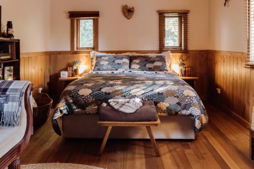 a bedroom with a large bed with a wooden floor at Hideaway Farmlet Romantic Cottage with Miniature Goats in Penguin