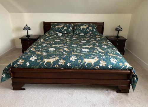 a bed with a floral comforter and two night stands at Entire cosy home from home country retreat in Holyhead