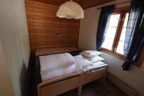 Habitación pequeña con cama con sábanas y almohadas blancas. en Villa Nurminiemi, en Koro