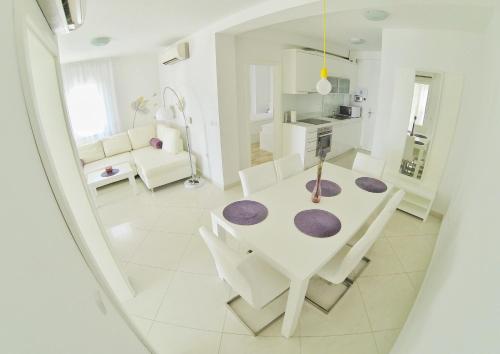 una sala da pranzo bianca con tavolo e sedie bianchi di Apartments Barbati a Novalja (Novaglia)