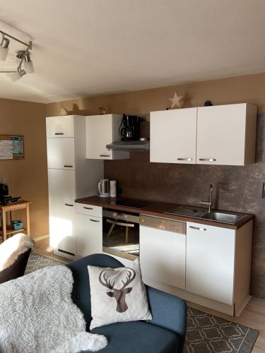 a kitchen with white cabinets and a blue chair at Haus Asslaber in Hochfilzen