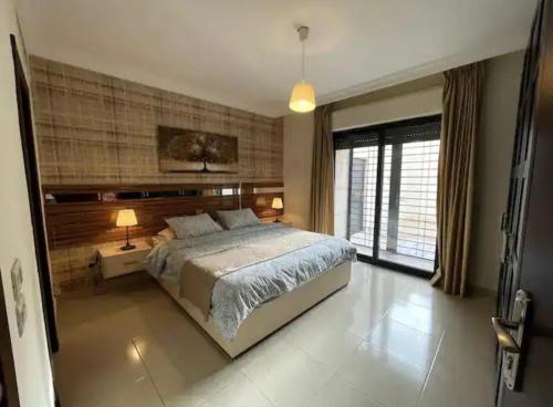 a bedroom with a large bed and a large window at Luxurious cozy apartment in Amman
