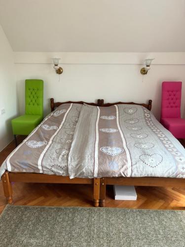 a bed in a room with two colorful chairs at Vila Vera in Divčibare