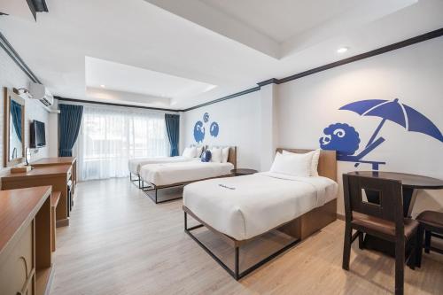 a hotel room with two beds and an umbrella on the wall at Kokotel Phuket Patong in Patong Beach