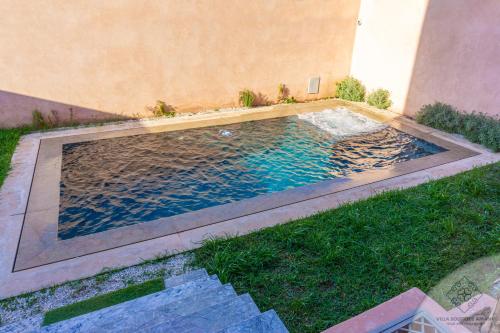 a swimming pool in the grass next to a building at Villa Boutique Amani in Marrakech