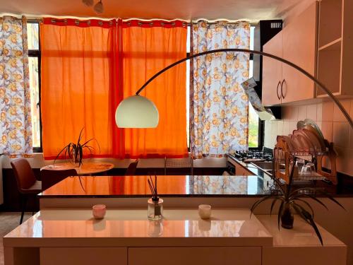 a kitchen with an orange curtain and a kitchen with a table at A 5 minutos do aeroporto! La Vie com estacionamento privado in Luanda