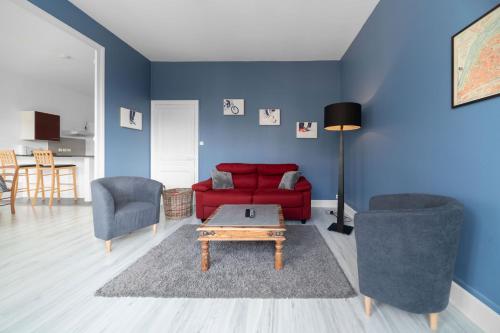 ein Wohnzimmer mit einem roten Sofa und 2 Stühlen in der Unterkunft Le Louis B - Appartement calme et lumineux proche Thermes in Vichy