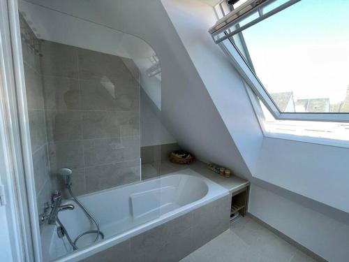 La salle de bains est pourvue d'une baignoire blanche et d'une fenêtre. dans l'établissement Maison T4 + Jardin SO, plages et commerces à pied, à Saint-Malo