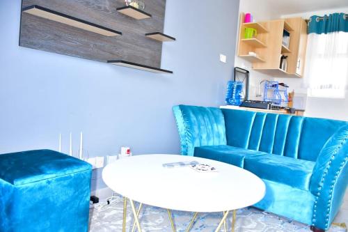 ナイロビにあるAqua Modern Studio Near Ngong Roadのリビングルーム(青いソファ、白いテーブル付)
