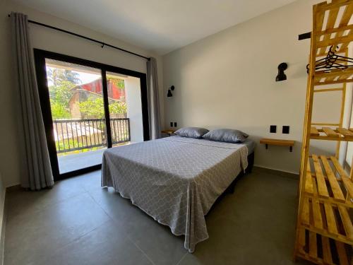 um quarto com uma cama e uma grande janela em Villa Julião em Ilhabela