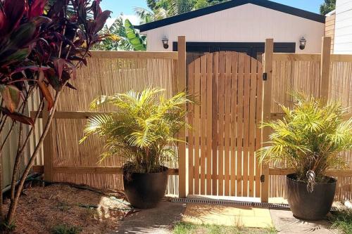 a wooden fence with two potted plants in front of a gate at Mango Tree Cottage in Forster