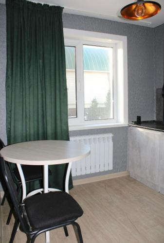 a table and chairs in a room with a window at Амстердам in Petropavlovsk