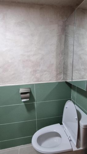 La salle de bains est pourvue de toilettes et d'un mur vert. dans l'établissement Stay be oom, à Jeju