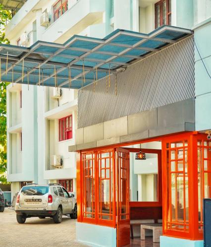 a building with orange doors and a car parked in front at Hotel Prasanth in Ernakulam