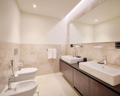 Grand Hyatt Kuwait Residences في الكويت: حمام مغسلتين ومرآة