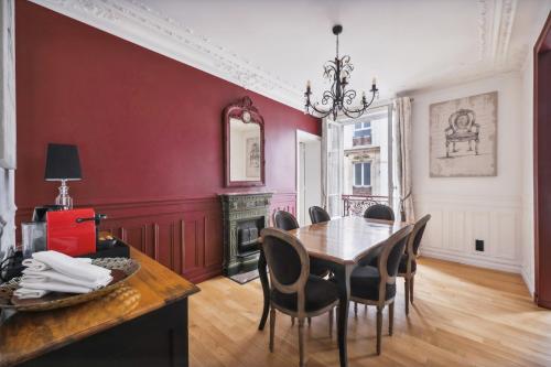 une salle à manger avec des murs rouges, une table et des chaises dans l'établissement Séjours Parisiens / Suite Le Royal / 4*, à Paris