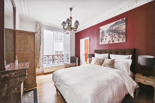 une chambre avec un grand lit avec un mur rouge dans l'établissement Séjours Parisiens / Suite Le Royal / 4*, à Paris