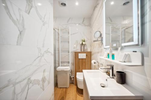 une salle de bain blanche avec un lavabo et des toilettes dans l'établissement Séjours Parisiens / Suite Le Royal / 4*, à Paris