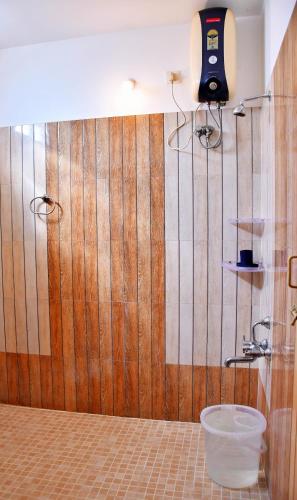 a bathroom with a wooden wall with a bucket at Revive Inn Pondy - Rooms & Villa in Puducherry